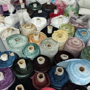 Vibrant mix of fabric rolls in various colors at a textile store, offering a broad selection.