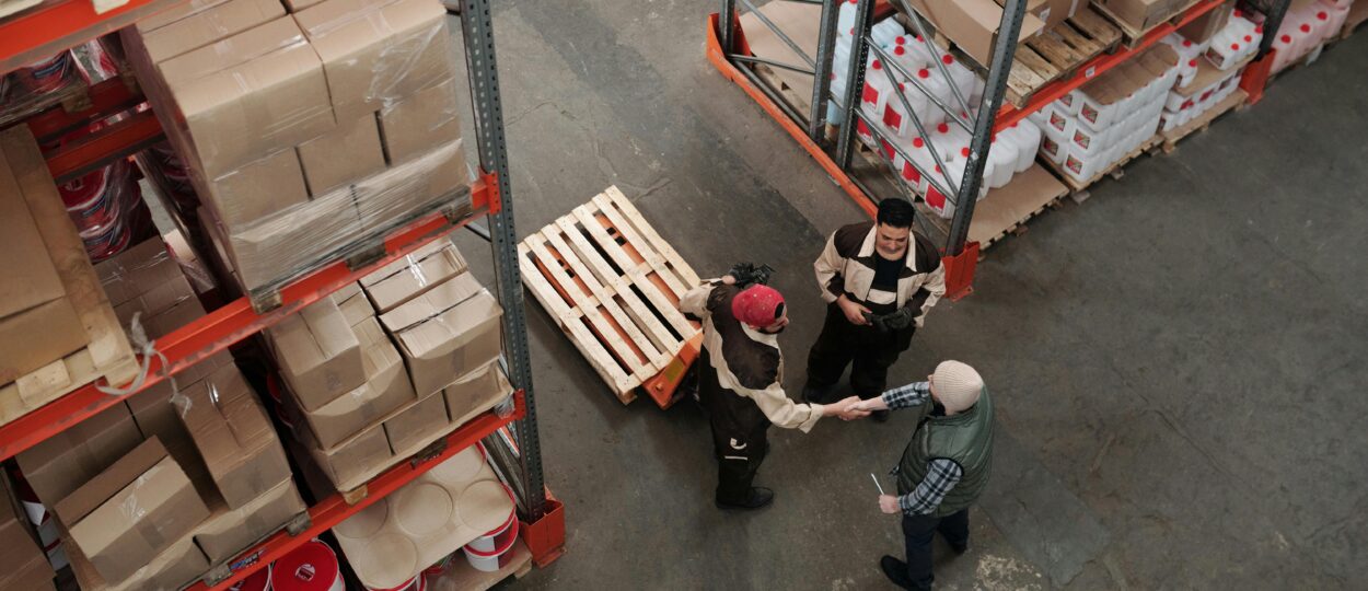 High angle view of workers shaking hands in a warehouse, symbolizing teamwork and logistics.